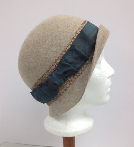 Shot ribbon in teal, and a fancy straw braid were both used to make the hat band, which is pleated into a bow on the right side.